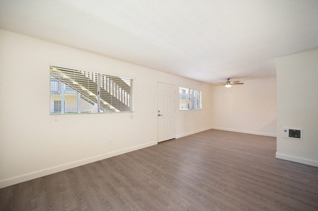 an empty living room with white walls and wood flooring