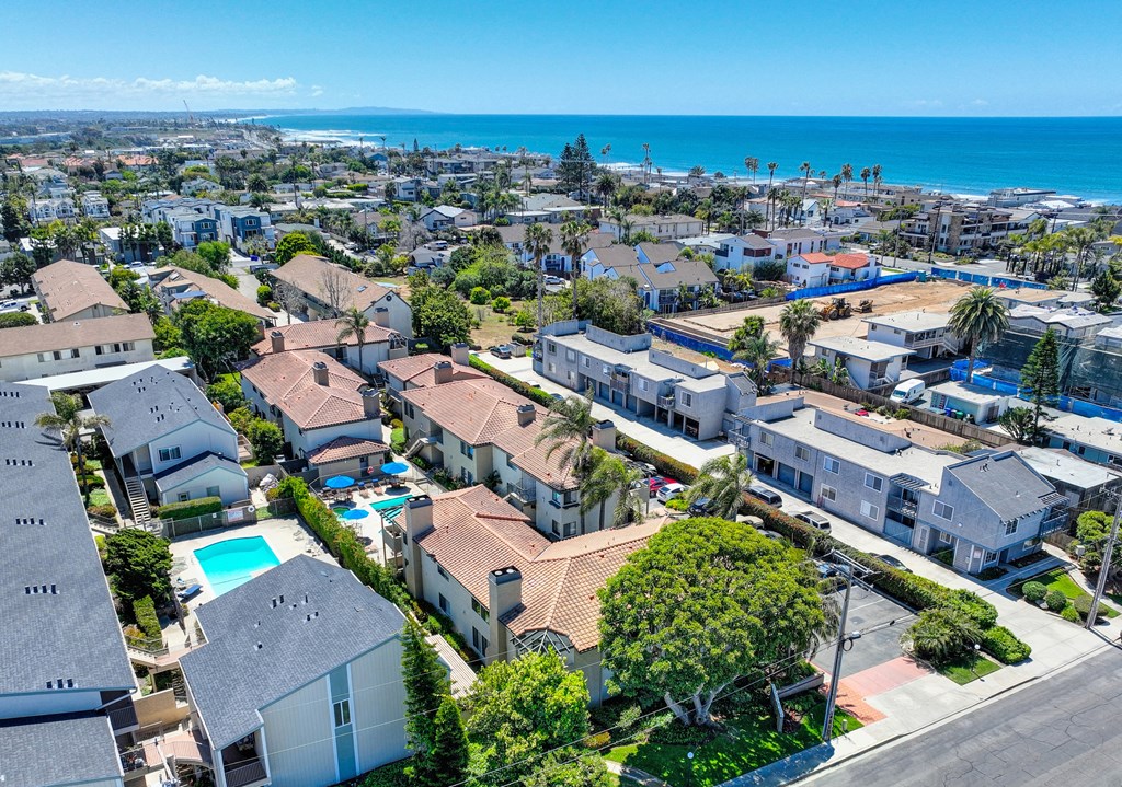 a group of houses with a pool and the ocean in the background