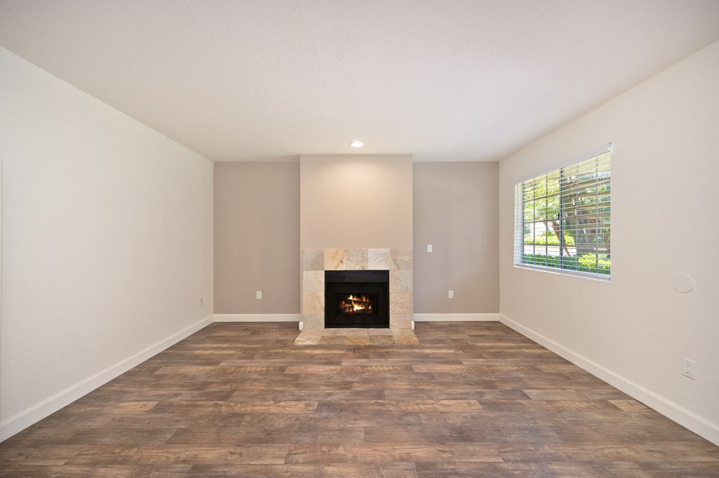 an empty living room with a fireplace and a window