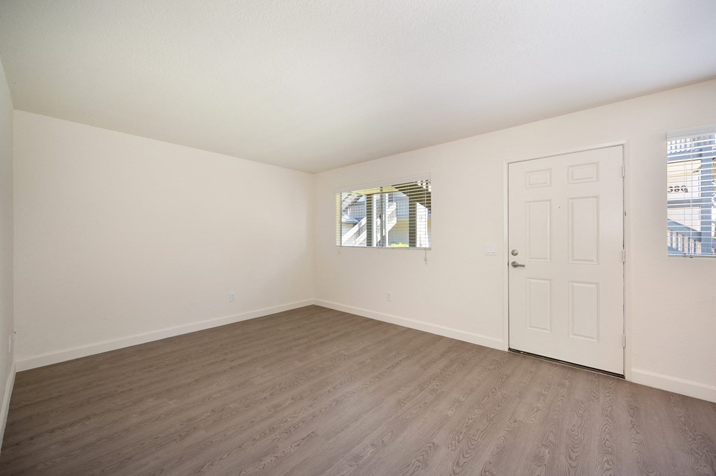 an empty living room with white walls and wood flooring