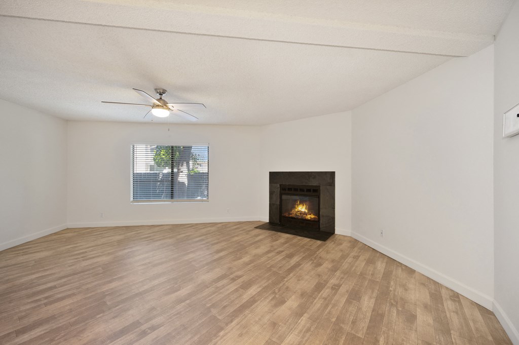 an empty living room with a fireplace and a ceiling fan