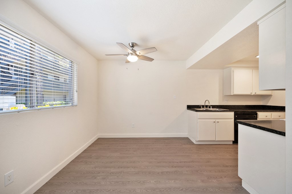 an empty kitchen with a window and a ceiling fan