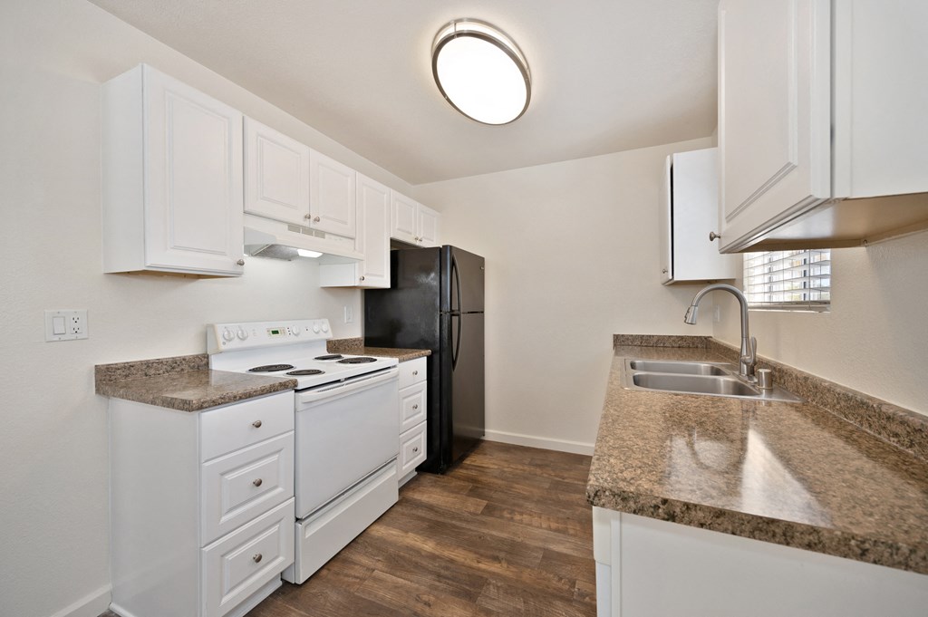 a kitchen with white cabinets and granite counter tops and a black refrigerator