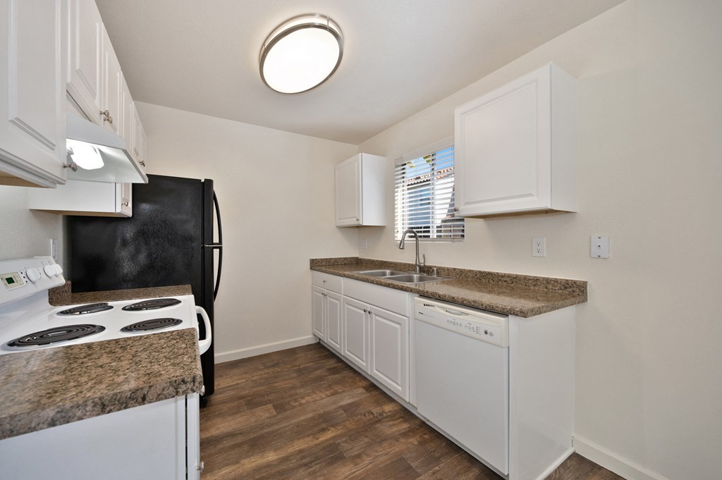 a kitchen with white appliances and granite counter tops and a black refrigerator