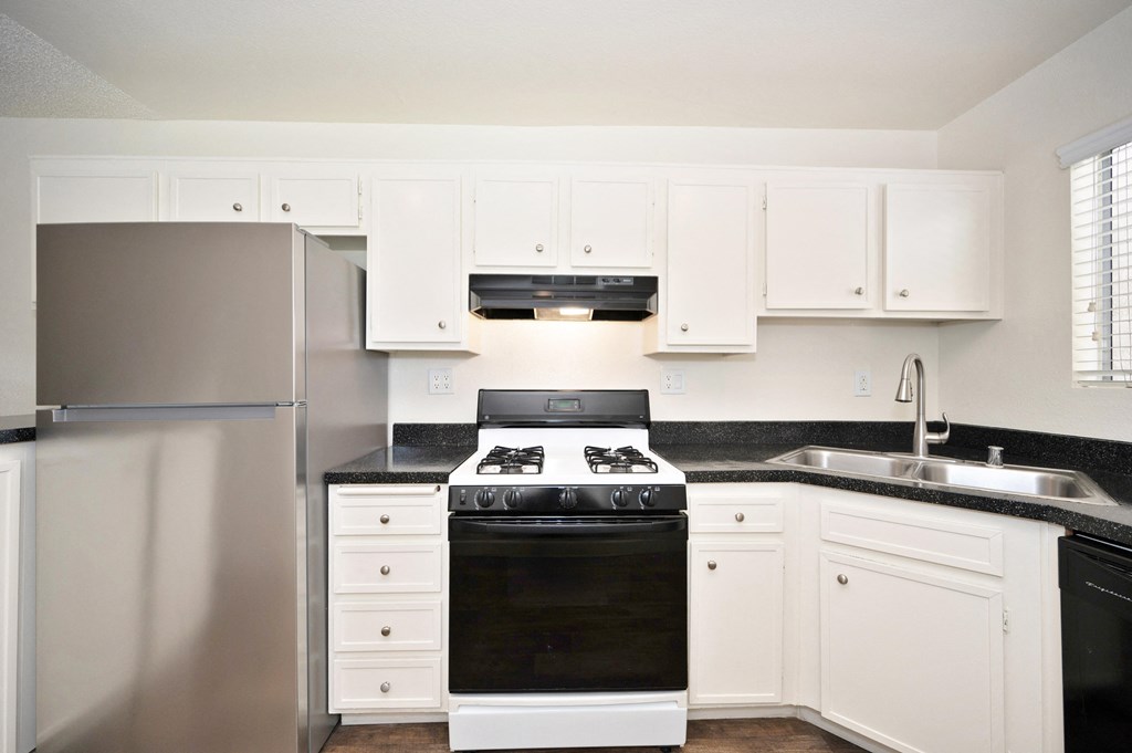 a kitchen with white cabinets and black appliances and a stainless steel refrigerator