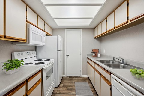 A kitchen with white appliances and wooden cabinets.