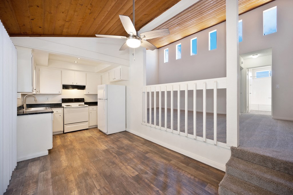 an open kitchen with white appliances and a ceiling fan