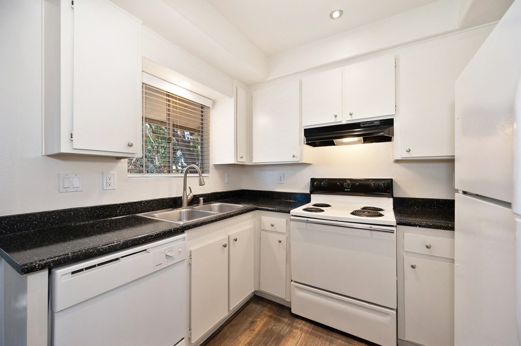 a kitchen with white appliances and black counter tops and white cabinets