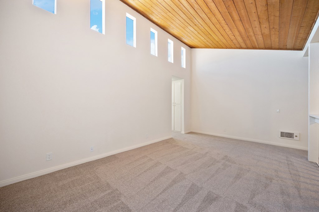 a room with carpet and white walls and a wooden ceiling