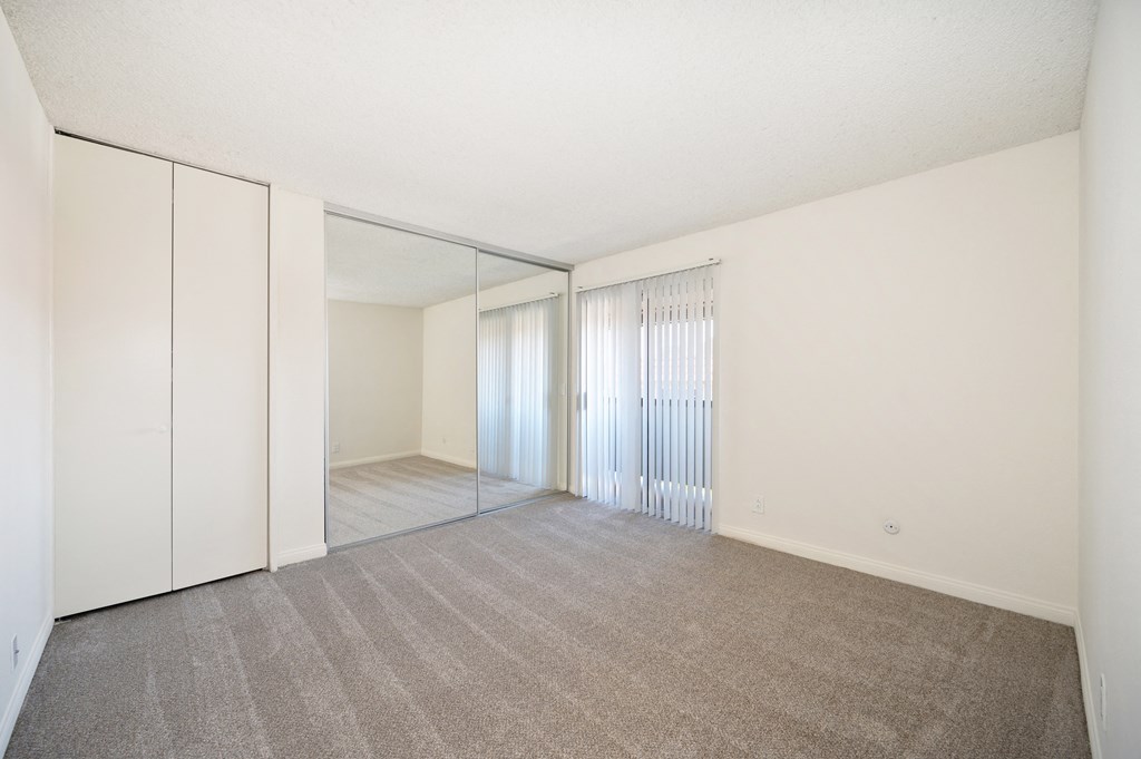an empty living room with mirrored closet doors and a carpeted floor