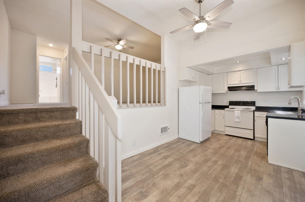 a white kitchen with a staircase in a house with white appliances