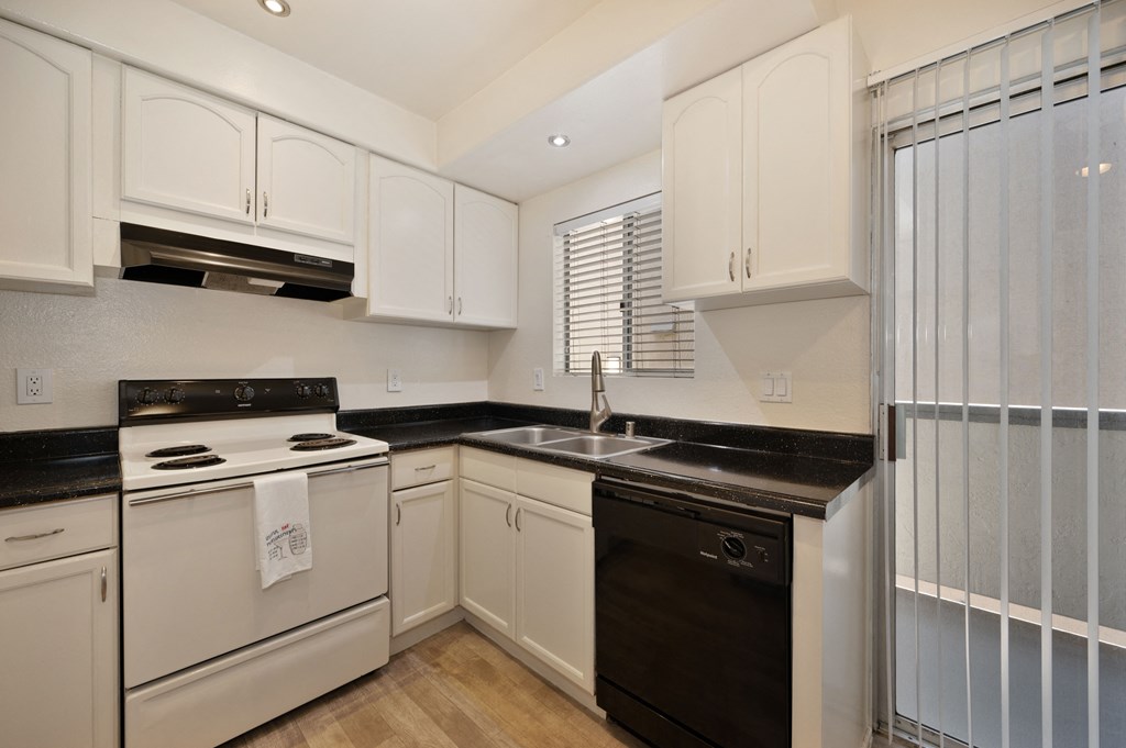 a kitchen with white cabinets and black counter tops and white appliances
