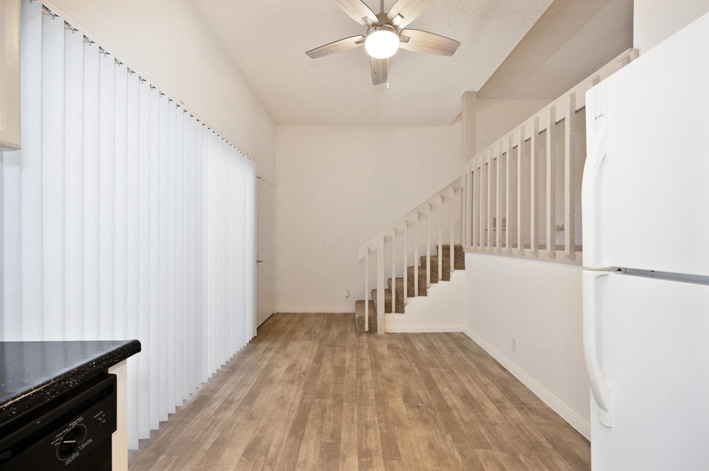 an open kitchen and living room with white walls and wood floors