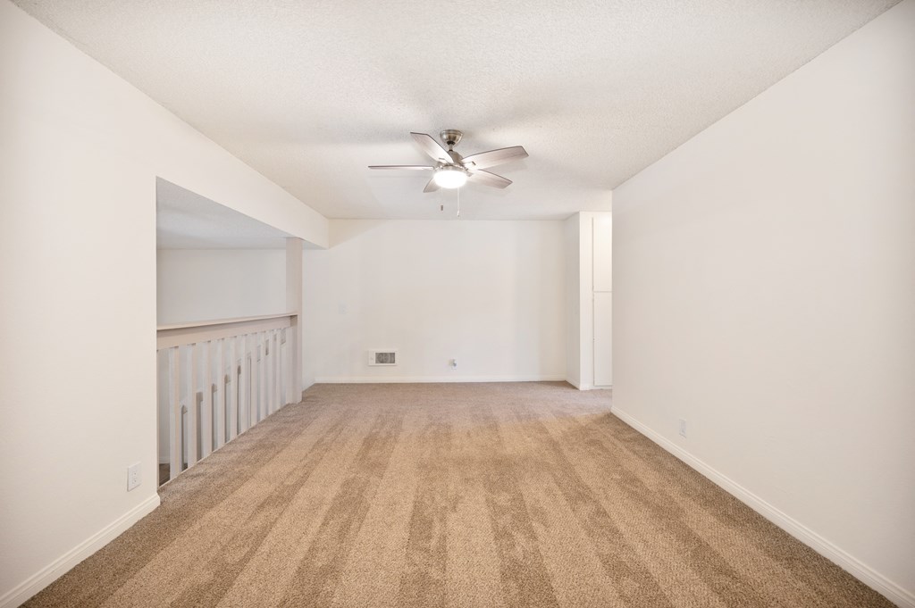 an empty living room with white walls and a ceiling fan