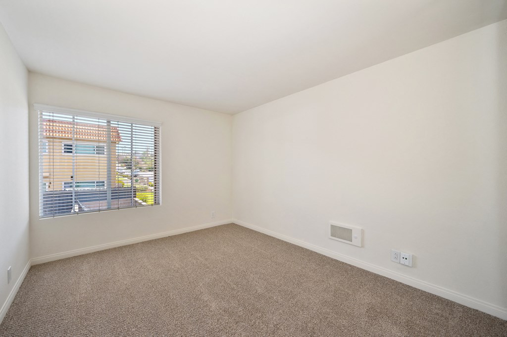 an empty living room with a window and carpet