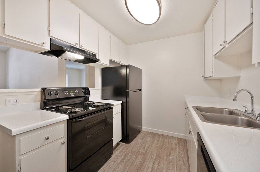 an empty kitchen with white cabinets and a black stove and refrigerator