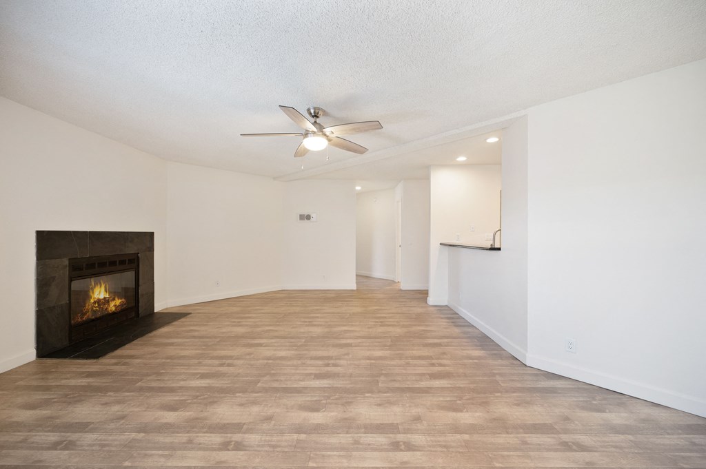 an empty living room with a fireplace and a ceiling fan