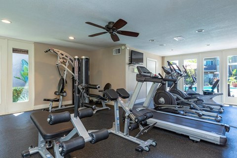 Community fitness center with ceiling fan and weight and cardio machines.