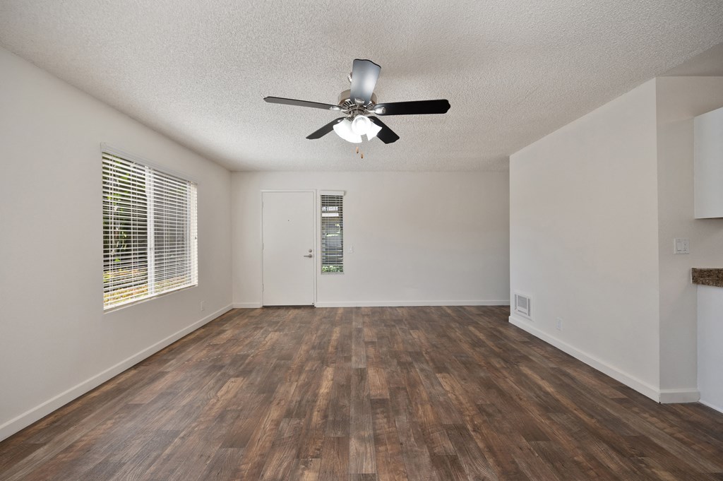 an empty living room with a ceiling fan and a window