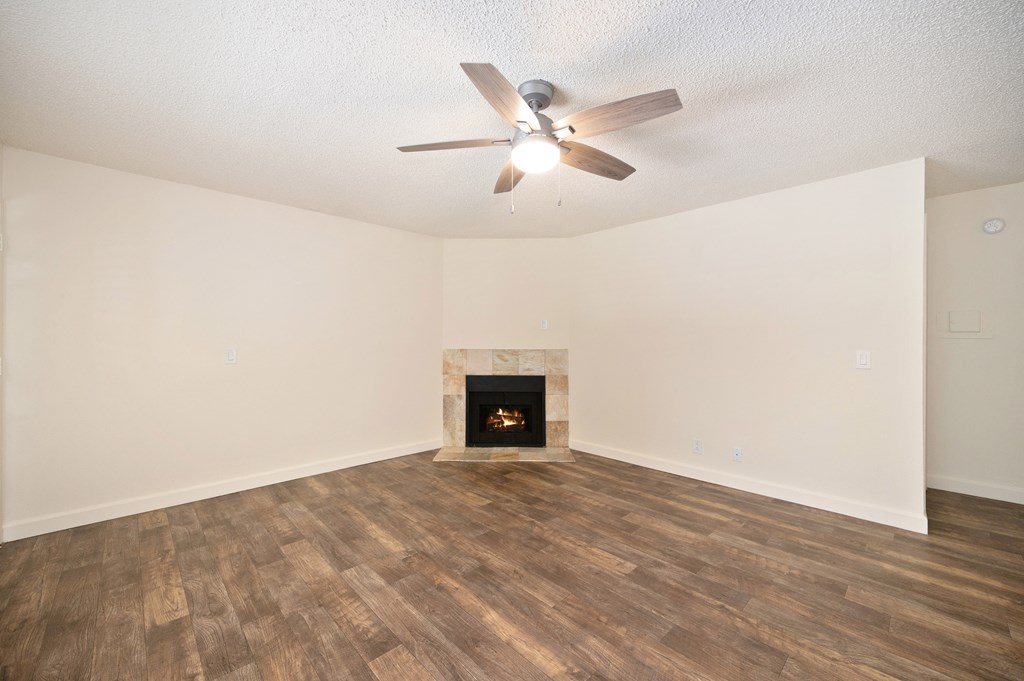 an empty living room with a fireplace and a ceiling fan