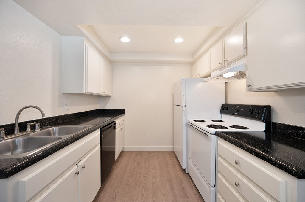 a kitchen with white appliances and black counter tops and white cabinets
