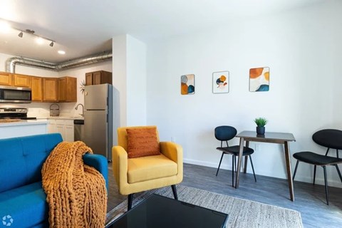 A living room with a blue couch, yellow chair, and a small table with chairs.
