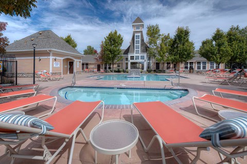 A pool surrounded by sun loungers and a building in the background.