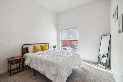 A bedroom with a large bed and a window overlooking a red building.