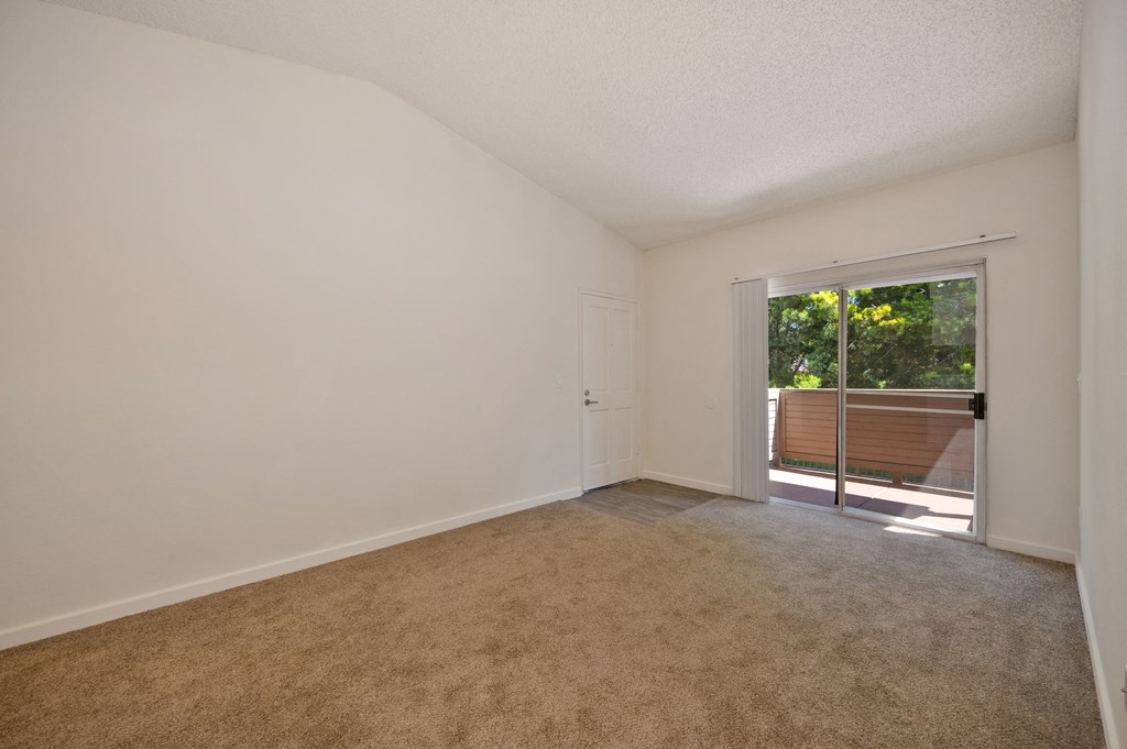 an empty living room with a sliding glass door to a patio