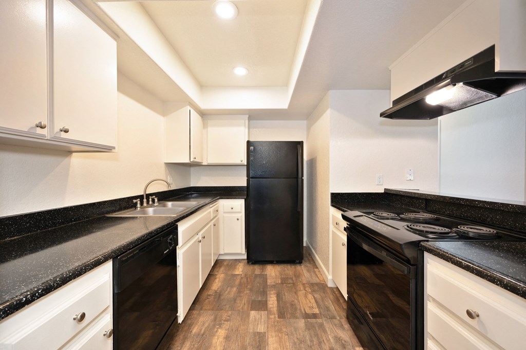 a kitchen with black counters and white cabinets and a black refrigerator