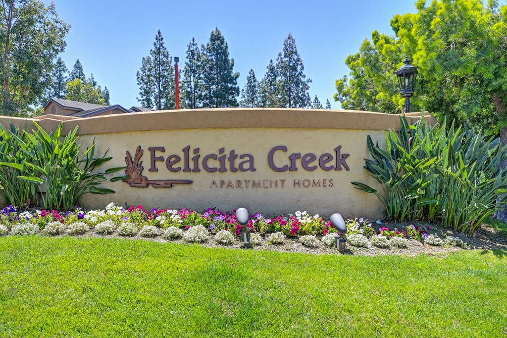 a sign apartment homes with flowers and grass