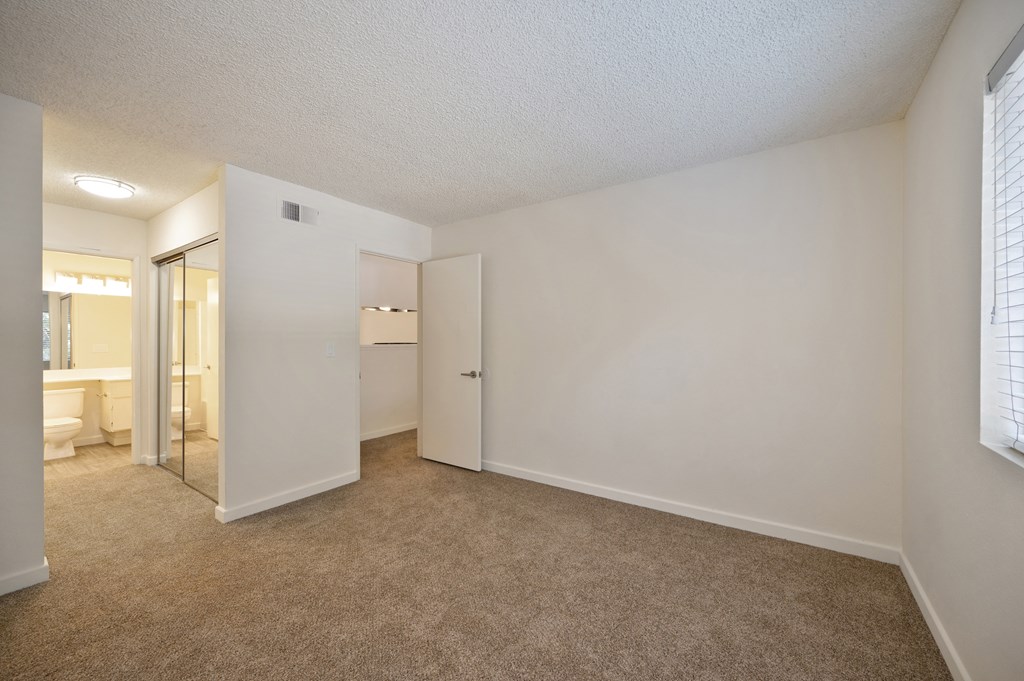 a spacious living room with a mirror and a bathroom