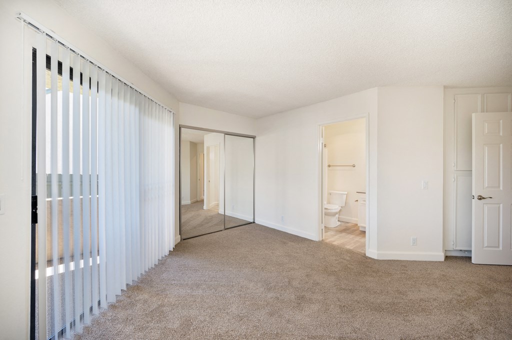 an empty living room with a mirrored closet and a door to a bathroom