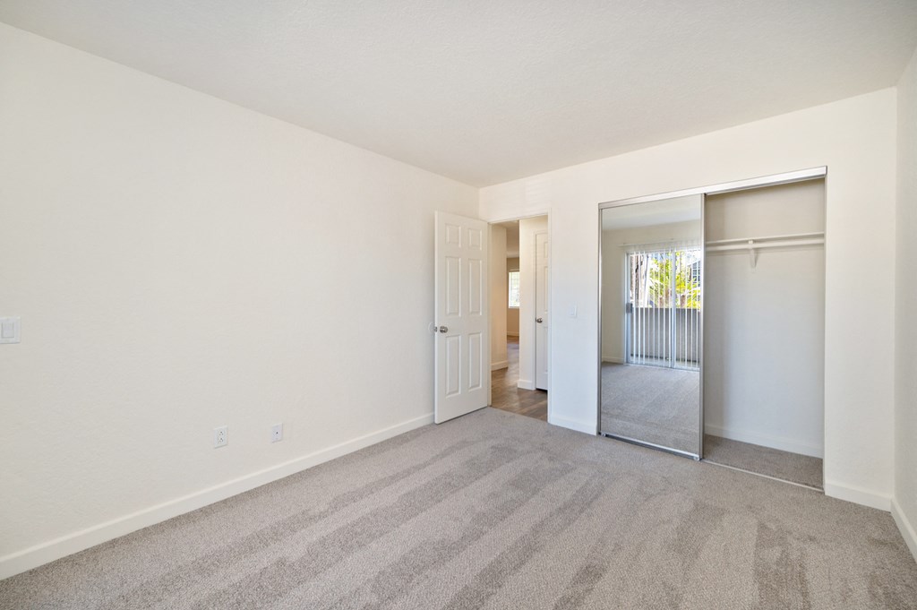 a spacious living room with carpet and a door to a bedroom