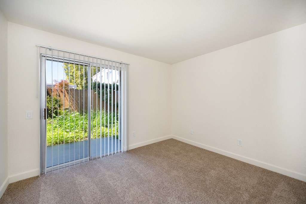 an empty living room with a sliding glass door to a yard