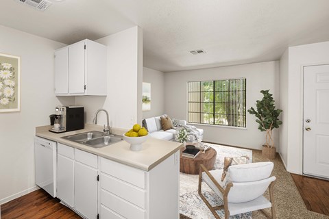 Carpeted living room and kitchen with wood-style vinyl plank flooring, white cabinets, and large window.