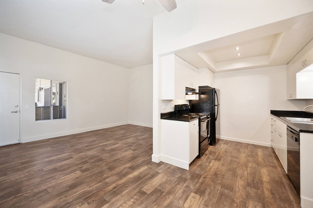 a kitchen and living room with a wood floor and white walls