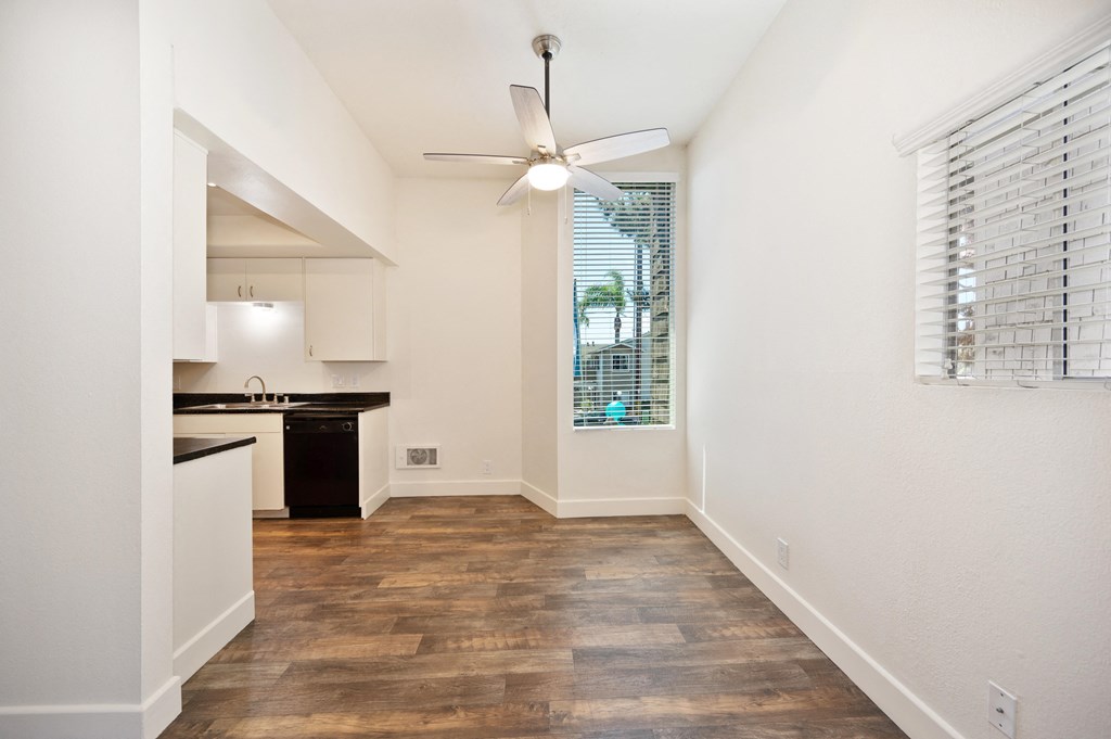 a spacious living room with a kitchen and a ceiling fan