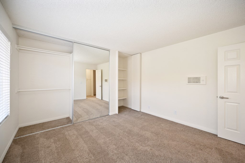 the living room of an apartment with carpet and white walls