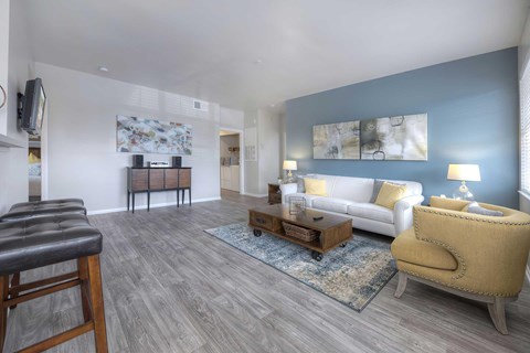 A living room with a white couch, a yellow armchair, and a wooden coffee table.