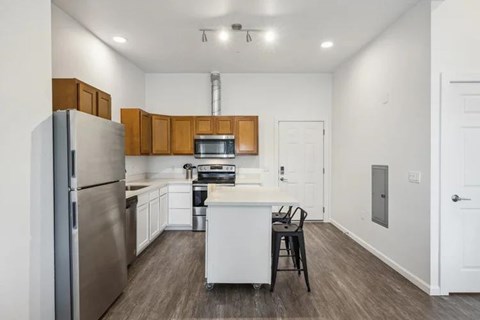 A kitchen with a refrigerator, oven, and sink.