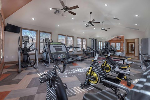 A gym with a variety of exercise equipment including treadmills, stationary bikes, and elliptical machines.