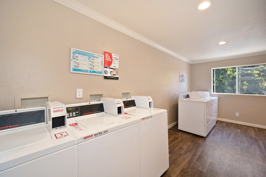 a laundry room with two washes and two dryers and a window