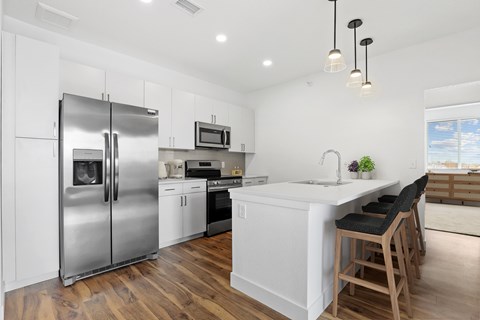 a white kitchen with a island and stainless steel refrigerator