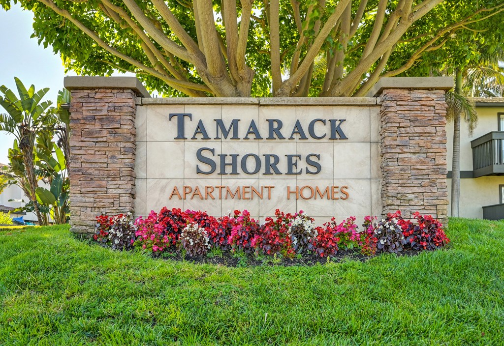 a sign for tamarack shores apartment homes in front of a tree