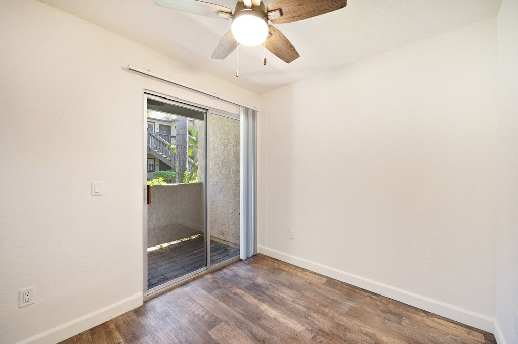 an empty living room with a ceiling fan and a sliding glass door to a patio