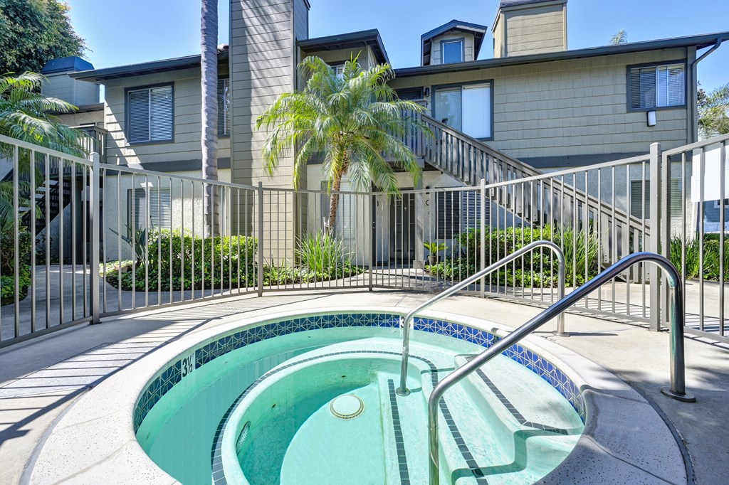 a small hot tub in a fenced in yard with a house in the background