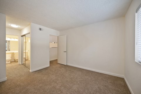 A bedroom with a carpeted floor and a window with blinds.