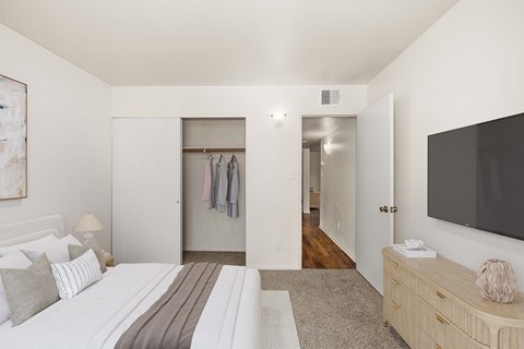 A bedroom with a large bed and a TV on the wall.