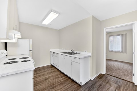 A kitchen with white appliances and cabinets with a window in the background.